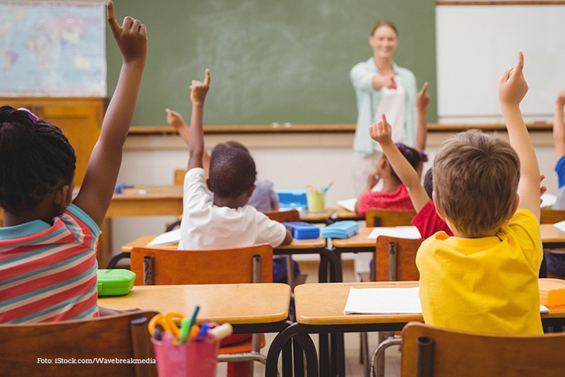 Schüler*innen sitzen im Unterricht und melden sich. 