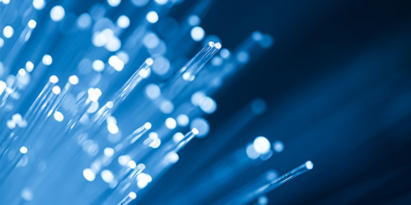 KI generiert: Das Bild zeigt eine Nahaufnahme von leuchtenden Glasfaserkabeln mit Bokeh-Effekt, die ein futuristisches und technologisches Gefühl vermitteln. Die hellen Punkte wechseln sich mit den schlanken Linien der Fasern ab und erzeugen eine dynamische Komposition.