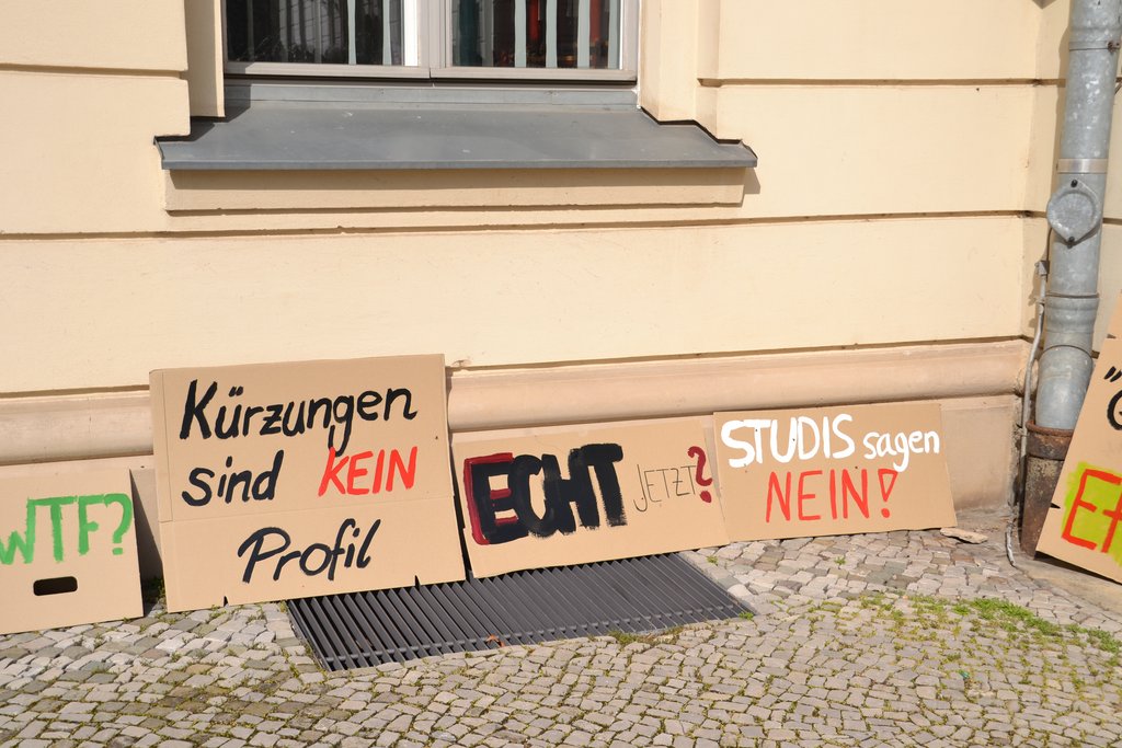 KI generiert: Auf dem Bild sind mehrere Protestplakate vor einer Hauswand zu sehen, die sich gegen Kürzungen aussprechen. Die Slogans beinhalten Botschaften wie "Kürzungen sind KEIN Profil" und "STUDIS sagen NEIN!".