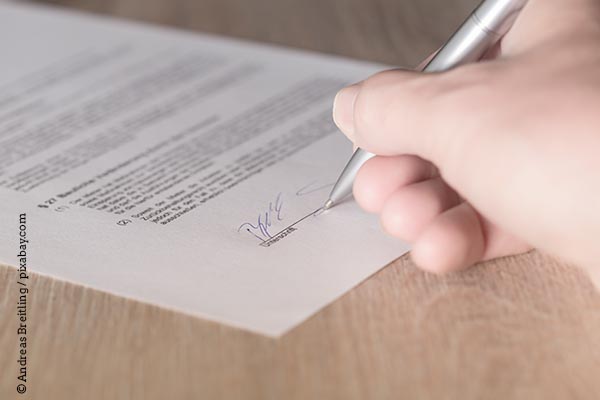 Eine Person unterschreibt ein Dokument.